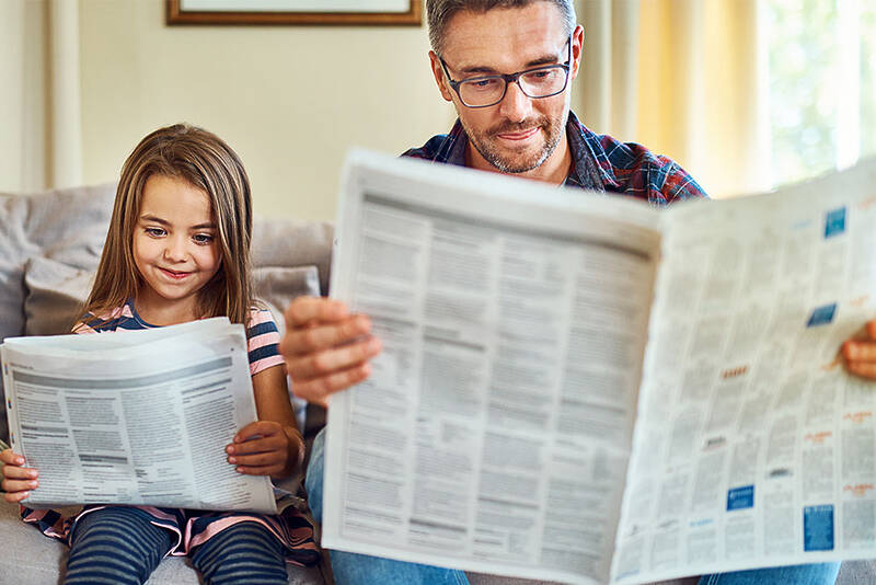 father and child reading newspapers