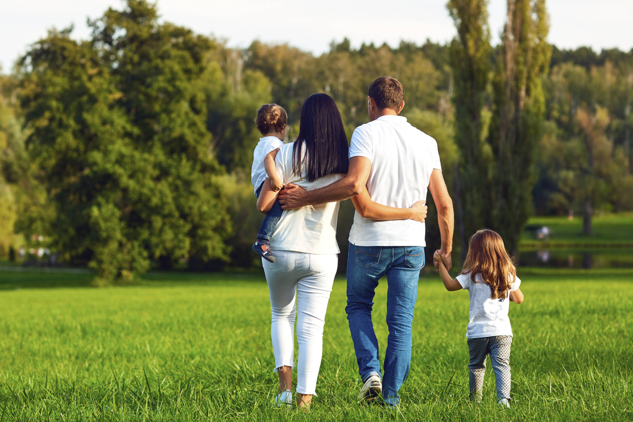 Rear View. Happy Family With Children Walking In The Park.